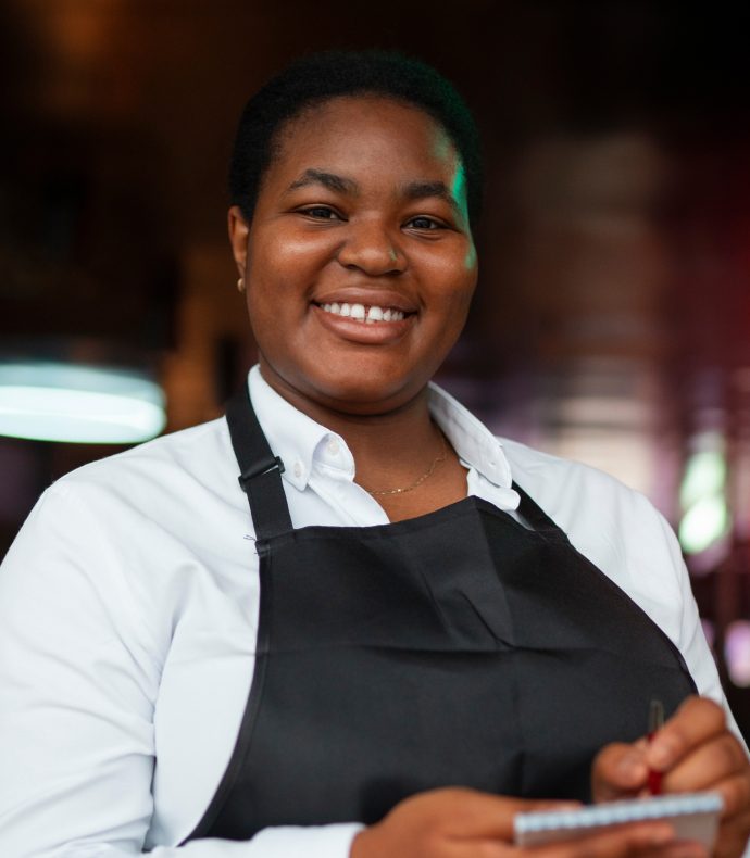 A member of the Dee's team smiling behind the pass, order pad in hand