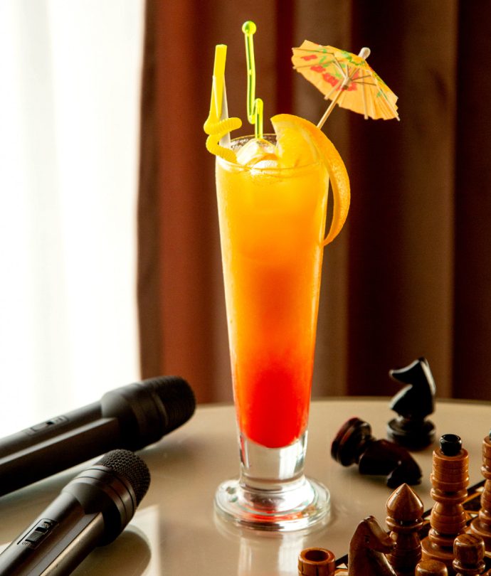 A tall layered cocktail beside two microphones on the lounge table